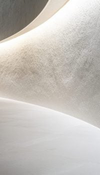 Close-up of a pristine white curved wall, subtly textured, against a light gray floor, minimalist design, soft lighting emphasizes the gentle curves and shadows, clean lines, elegant composition filling the frame --ar 16:9 --v 6.1 Job ID: 5f97644a-2d77-405f-9c7d-bf92992ceb42