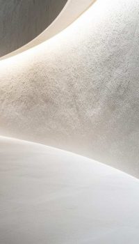 Close-up of a pristine white curved wall, subtly textured, against a light gray floor, minimalist design, soft lighting emphasizes the gentle curves and shadows, clean lines, elegant composition filling the frame --ar 16:9 --v 6.1 Job ID: 5f97644a-2d77-405f-9c7d-bf92992ceb42